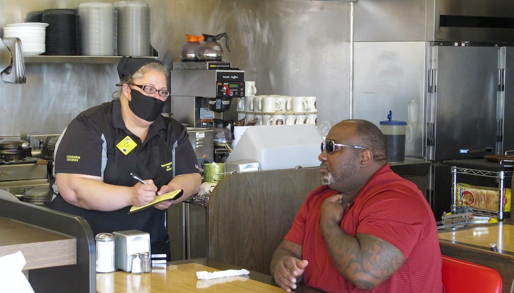 A customer orders food at a Waffle House restaurant in Savannah, Georgia, after restaurants statewide were allowed to resume dine-in service with restrictions. (AP Photo/Russ Bynum)