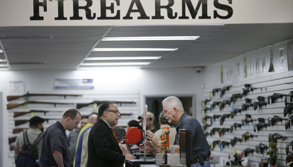 Sales associate Mike Conway, right, shows Paul Angulo a pistol at the Bullseye Sport gun shop in Riverside, Calif. (AP)