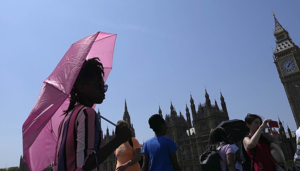 A woman shelters from the sun with an umbrella as she walks down Westminster Bridge in London, July 19, 2022. (AP)