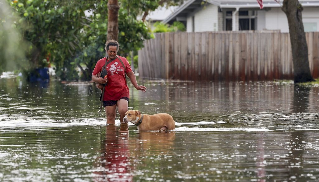 Una mujer camina con su perro a través de las inundaciones del huracán Helene en el barrio de Shore Acres, el 27 de septiembre 2024, en San Petersburgo, Florida. (AP)