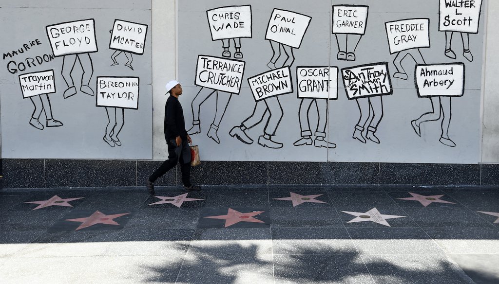 A man walks past a mural of black victims of police brutality on Hollywood Boulevard in Los Angeles on June 15, 2020, a day after a large protest march there. (AP)