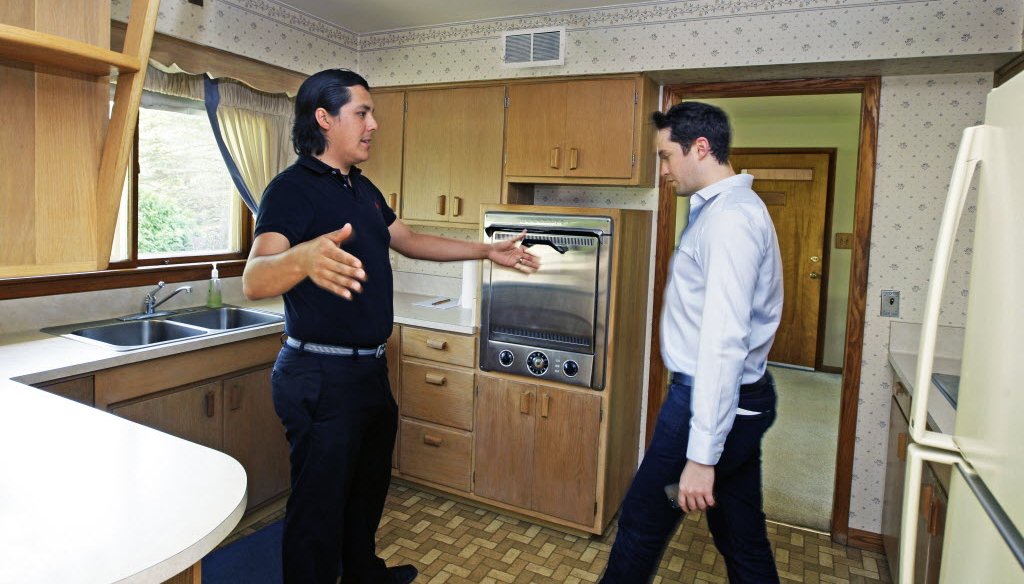 David Gonzalez, left, talks about changes he would make to the kitchen while looking at this 1950's suburban Milwaukee home for sale with real estate agent Wil Poull, right, in May 2013. 