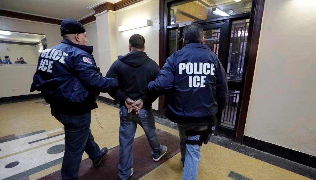 Immigration and Customs Enforcement officers escort an arrestee in an apartment building in the Bronx on March 3, 2015, during a series of early-morning raids. (AP/Richard Drew)