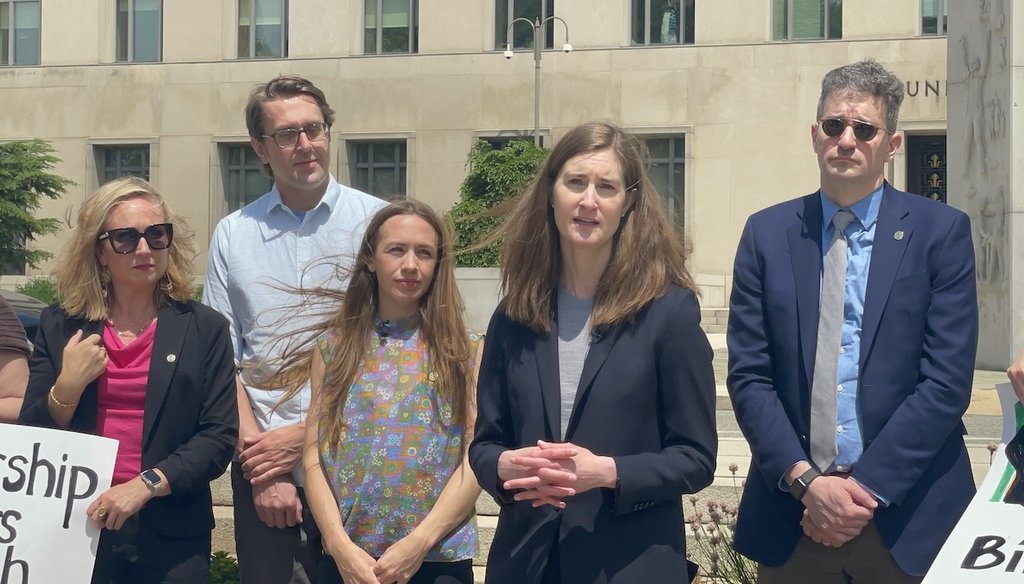 Attorney Carrie DeCell, second from right, speaks about her client's lawsuit against a Trump administration visa policy outside the federal courthouse in Washington, D.C., on May 13, 2026. (Louis Jacobson / PolitiFact)