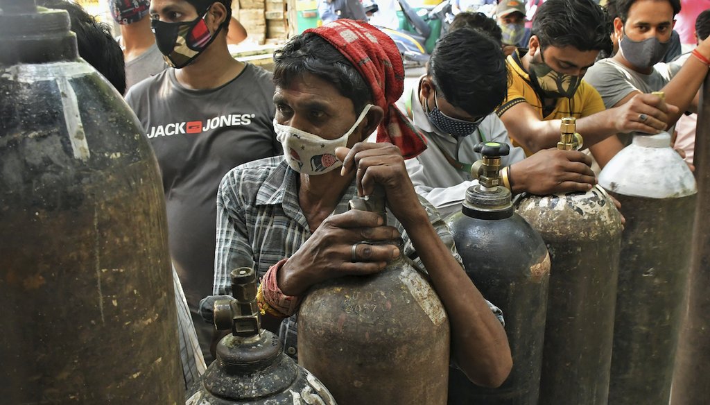 People wait to refill oxygen cylinders for COVID-19 patients at a gas supplier in New Delhi, India, Saturday, May 8, 2021. Infections have swelled in India since February in a disastrous turn blamed in part on more contagious variants. (AP)
