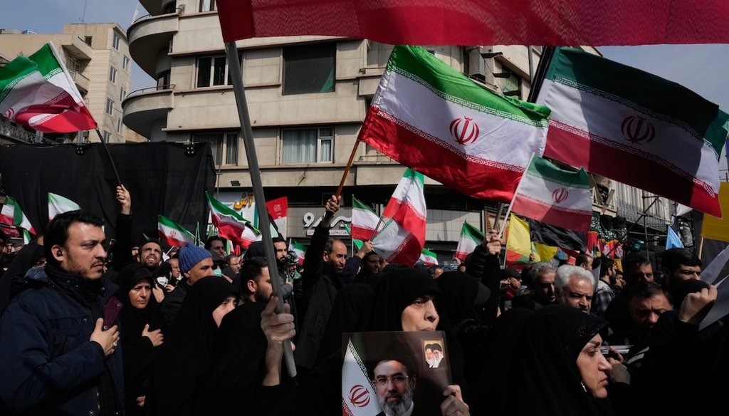 Mourners wave Iranian flags during the funeral procession for senior Iranian military officials and civilians killed during the U.S.-Israel campaign as one of them holds a poster of Ayatollah Mojtaba Khamenei,, in Tehran, Iran, March 11, 2026. (AP)