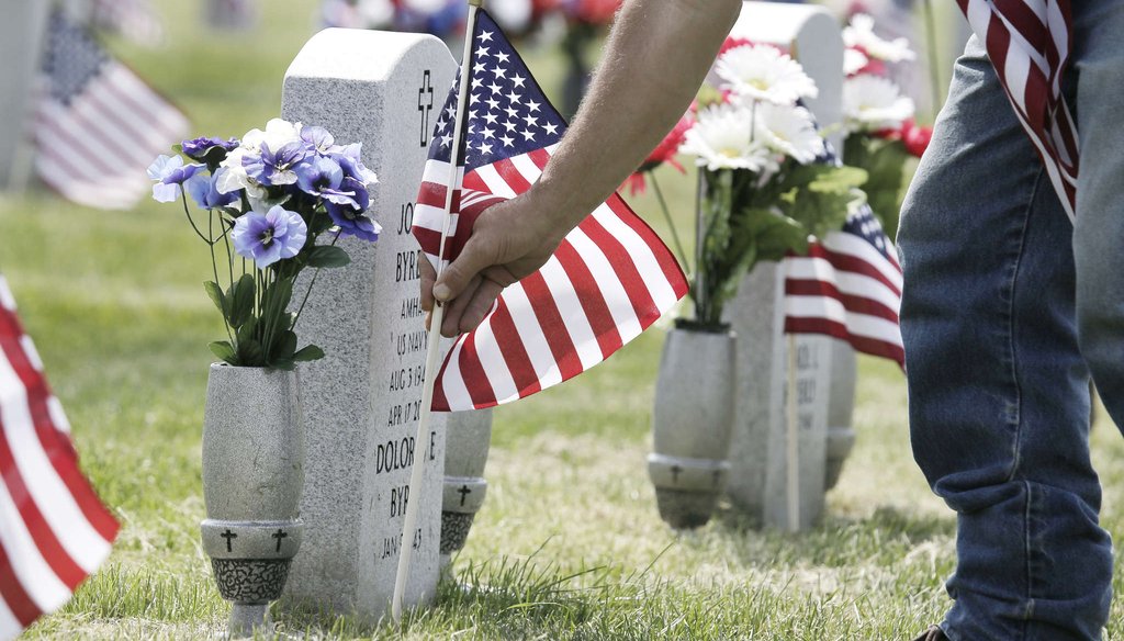 An employee at Gloucester County Veterans Memorial Cemetery in Monroe Township replaces a broken American flag on a veteran's grave. ELIZABETH ROBERTSON / Inquirer Staff Photographer