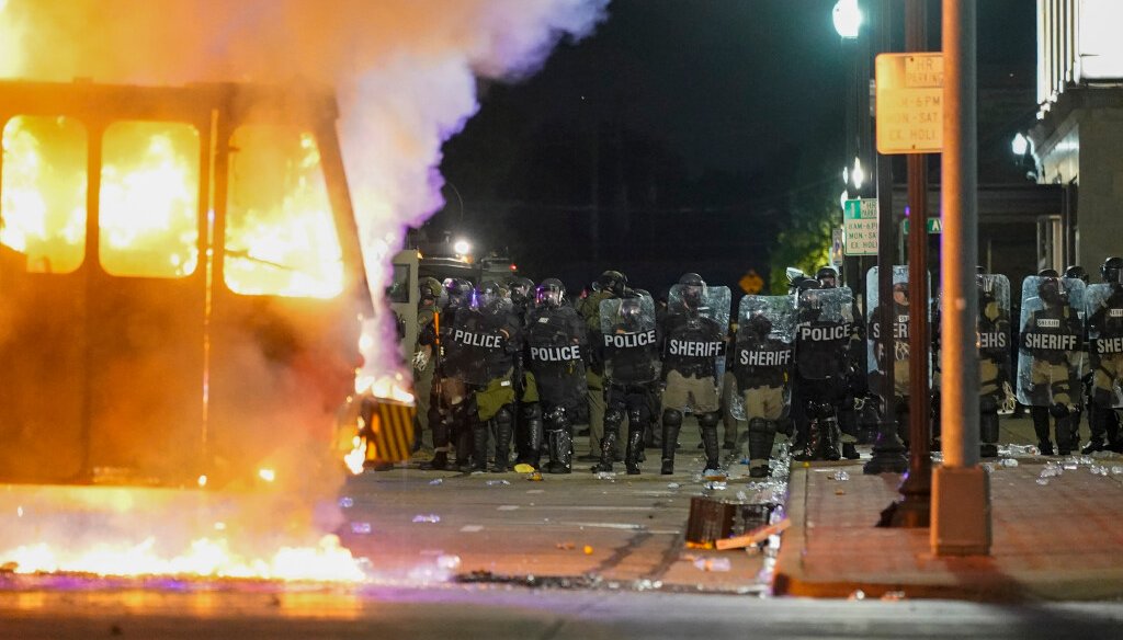 Police stand near a garbage truck ablaze during protests over the shooting of Jacob Blake in Kenosha on Aug. 24, 2020