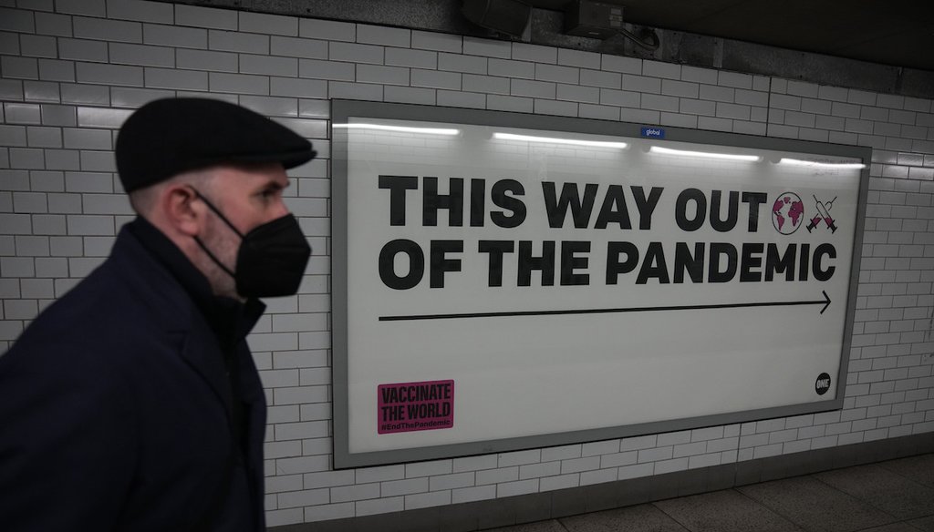 A man wearing a face mask to curb the spread of coronavirus walks past a health campaign poster in an underpass in London, on Jan. 27, 2022. (AP)