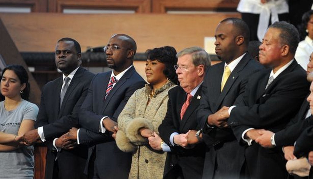 The Rev. Raphael Warnock, third from the left, and other speakers hold hands while singing "We Shall Overcome" at the conclusion of the Martin Luther King Jr. commemorative service. Photo credit: Kent Johnson/AJC.