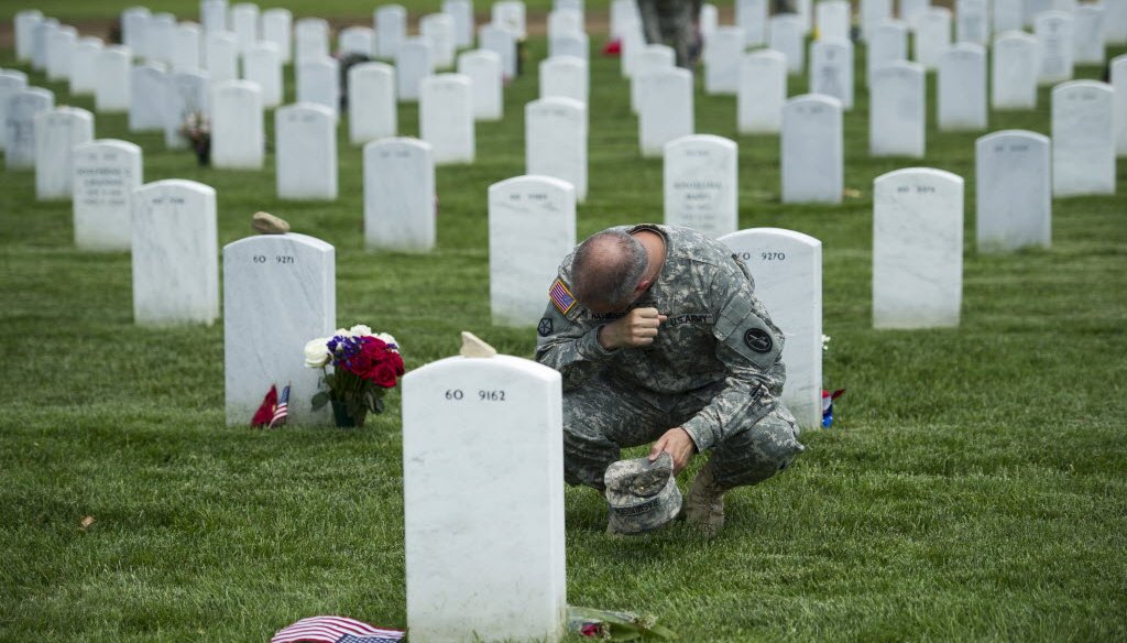An Army colonel wipes away tears as he visits a grave at Arlington National Cemetery while placing flags at grave sites ahead of Memorial Day 2014.