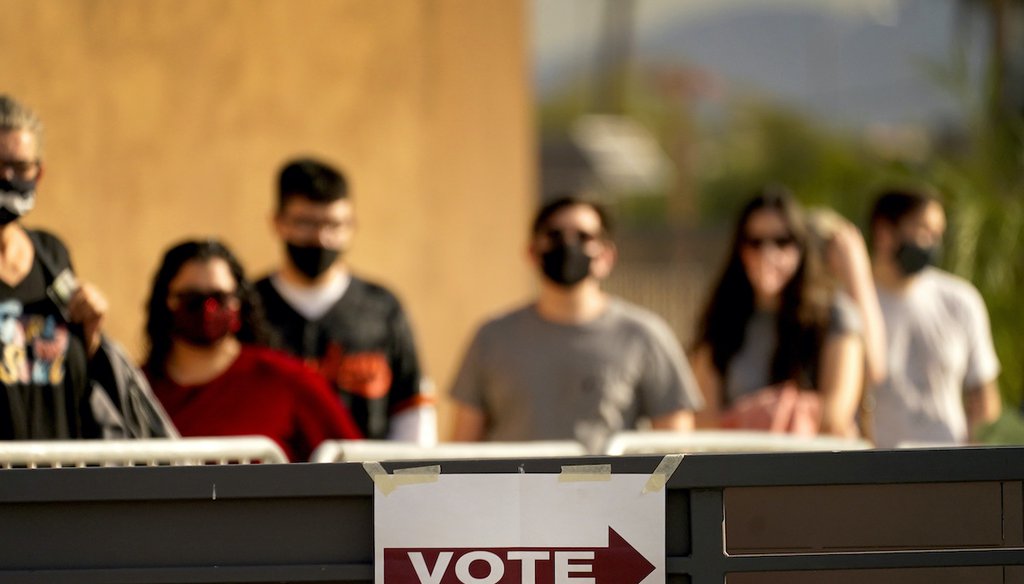In this Tuesday, Nov. 3, 2020 file photo, Voters stand in line outside a polling station, on Election Day in Mesa, Ariz.