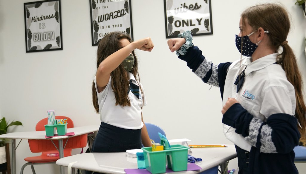 Students Sofia Senra, left, and Emma Orell, right, bump fists as they work on a lesson together at iPrep Academy on the first day of school, Monday, Aug. 23, 2021, in Miami.  (AP)