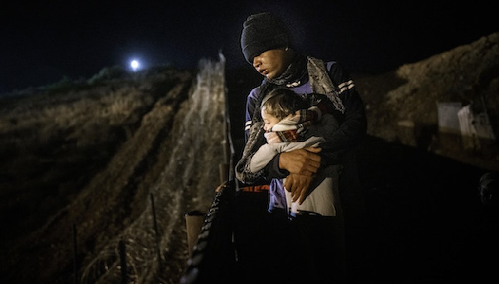 A member of a Honduran migrant holds a baby on top[ of a border fence in hopes of entering the United States to San Diego, from Tijuana, Mexico, Wednesday, Dec. 26, 2018. (AP)