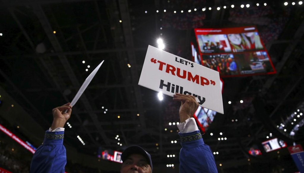 An attendee holds signs on the final day of the Republican National Convention at the Quicken Loans Arena in Cleveland, July 21, 2016. (New York Times)