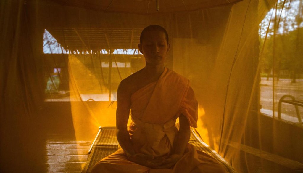 A novice monk takes part in evening meditation, under his mosquito net, in the monastery within Wat Dhammakaya in Bangkok, Dec. 12, 2016. (Lauren DeCicca/The New York Times)