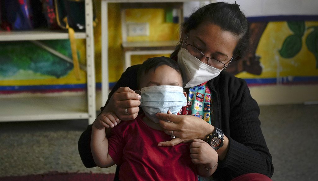 A teacher fixes a student's mask on their first day back to in-person learning amid the COVID-19 pandemic on Monday, Jan. 17, 2022. Associated Press.