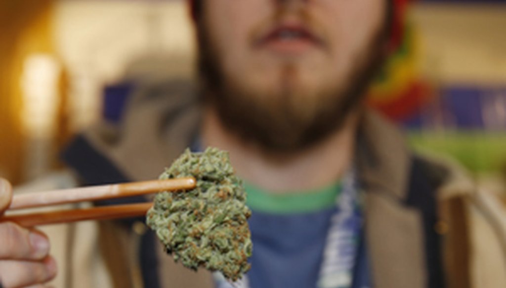 Sales associate Matt Hart uses chopsticks to hold a bud of Lemon Skunk, the strain of highest potency available at the 3D Dispensary, in Denver. (AP / David Zalubowski)