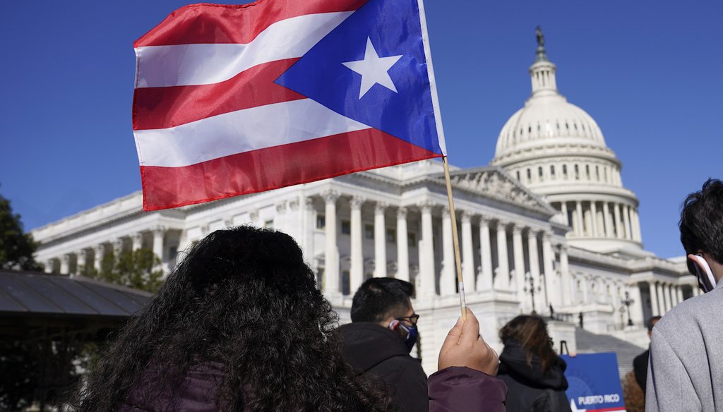 Una mujer alza la bandera de Puerto Rico durante una conferencia de prensa sobre la categoría de estado de la isla en el Capitol Hill, Washington, el 2 de marzo de 2021. (AP)