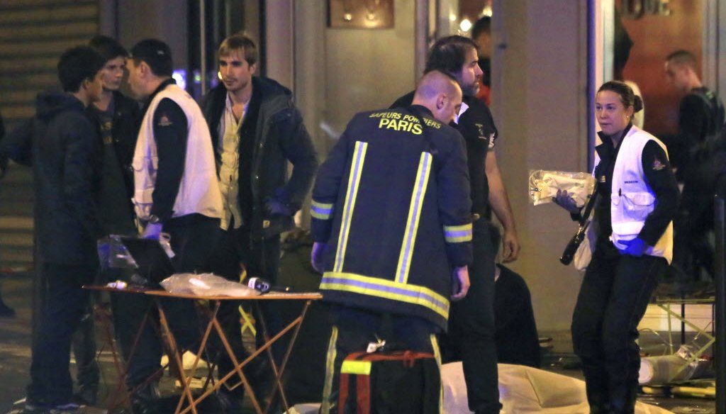 Rescue workers at the scene as victims lay on the pavement outside a Paris restaurant on Nov. 13, 2015. (AP photo)