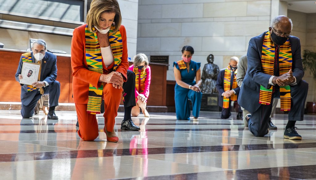 House Speaker Nancy Pelosi of Calif., center, and other members of Congress, kneel and observe a moment of silence at the Capitol's Emancipation Hall. (AP Photo/Manuel Balce Ceneta)