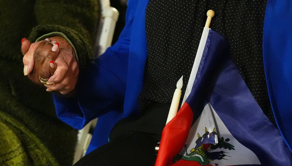 People hold hands and a Haitian flag during a vigil amid the legal battle to end TPS for Haitians in February 2026 at the Little Haiti Cultural Complex in Miami. (AP)