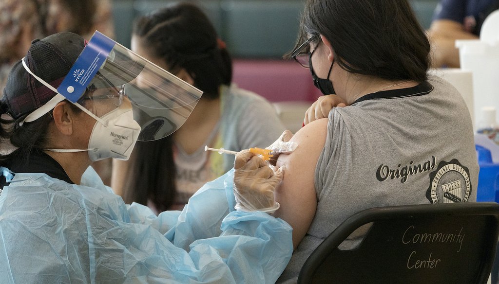 Guadalupe Flores, 15, right, from East Los Angeles, gets vaccinated with the Pfizer's COVID-19 vaccine by licensed vocational nurse Rita Orozco, far left, at the Esteban E. Torres High School in Los Angeles, Thursday, May 27, 2021. (AP)