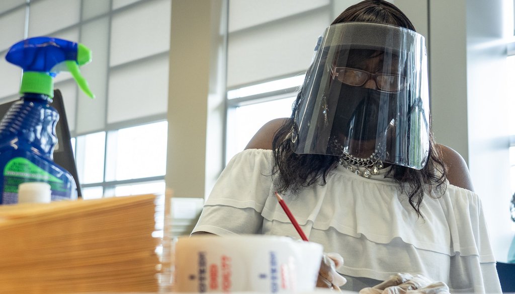 A poll worker in Wayne County wears PPE during Michigan Primary voting (Ryan Garza, Detroit Free Press)
