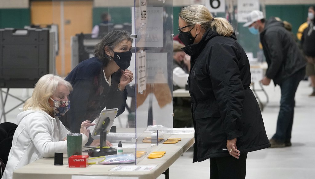 Poll Worker Suzan Winfrey, center left, speaks through a plastic barrier while assisting a voter in a polling station at Marshfield High School, Tuesday, Nov. 3, 2020, in Marshfield, Mass. (AP)