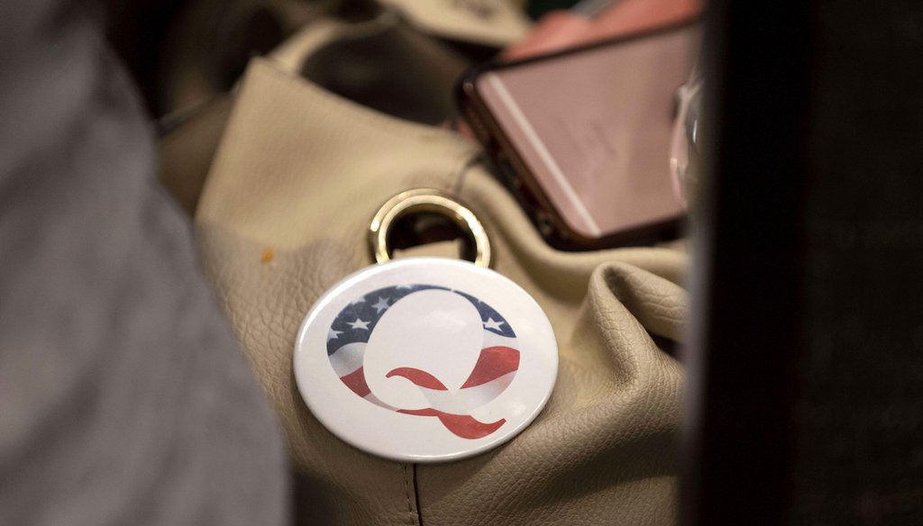 A QAnon button sits affixed to the bag of an attendee of an election integrity event in Omaha, Neb., Aug. 27. Former President Donald Trump continues to embrace the conspiracy theory, even as the number of frightening incidents linked to QAnon rise. (AP)