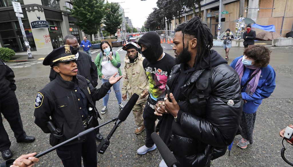 Seattle Police Chief Carmen Best, left, talks with activist Raz Simone, right front, and others near a plywood-covered and closed Seattle police precinct behind them on June 9, 2020. (AP)