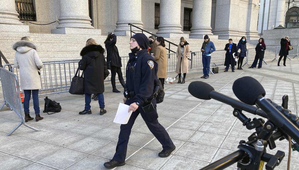 News reporters and others wait to enter the Thurgood Marshall United States Courthouse for the sex trafficking trial of Ghislaine Maxwell in New York City on Friday, December 3, 2021. An NYPD officer walks by microphones set up by the media. (AP)