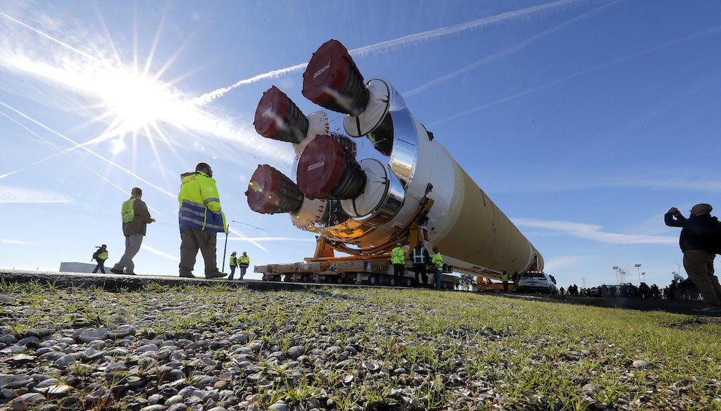 Security and safety personnel walk with the core stage of NASA's Space Launch System rocket as it is moved to the Pegasus barge, at the NASA Michoud Assembly Facility where it was built, in New Orleans, Wednesday, Jan. 8, 2020. (AP)