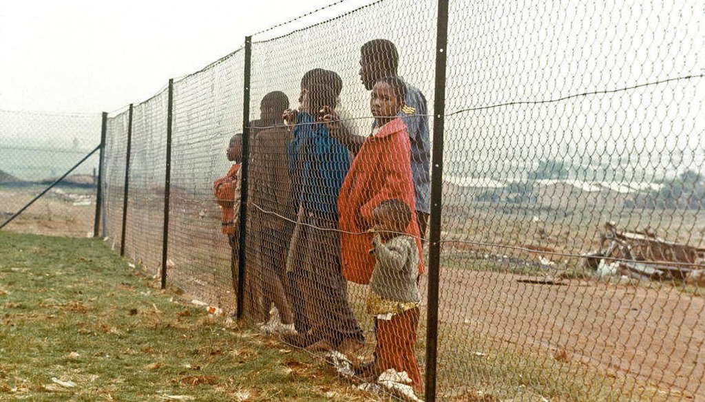 Children stand behind a fence that separates them from the white community near Johannesburg in 1973 (UN Photo) 