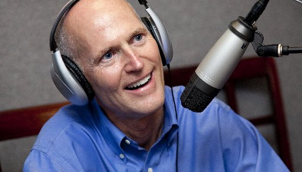 We couldn't find a picture of Florida Gov. Rick Scott reading a newspaper. Here he is during a radio interview.