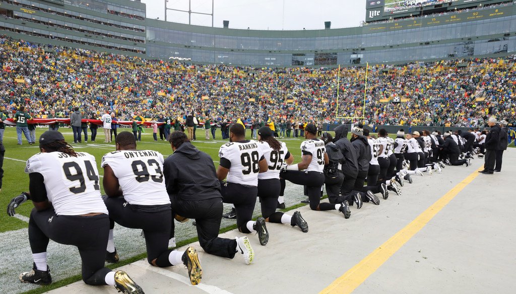 New Orleans Saints players kneel briefly before the national anthem, then stand and lock arms during the anthem, prior to their game against the Green Bay Packers at Lambeau Field in Green Bay, Wis., on Oct. 22, 2017. (Jeffrey Phelps/Associated Press)