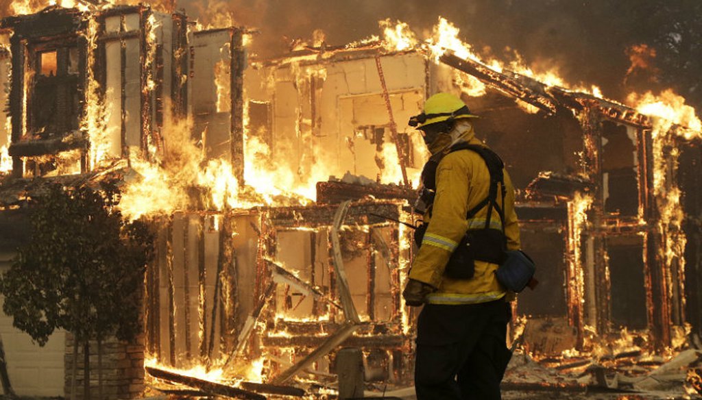 A firefighter monitors a house burning in Santa Rosa, Calif., Monday, Oct. 9, 2017. Wildfires whipped by powerful winds swept through Northern California causing residents to flee to safety through smoke and flames as homes burned. (AP Photo/Jeff Chiu)