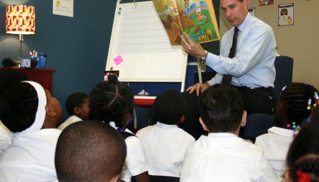 Gov. Scott Walker, shown here reading to first-graders at a private school in Milwaukee in September 2014, made historic cuts to public education funding but later restored some of the money.
