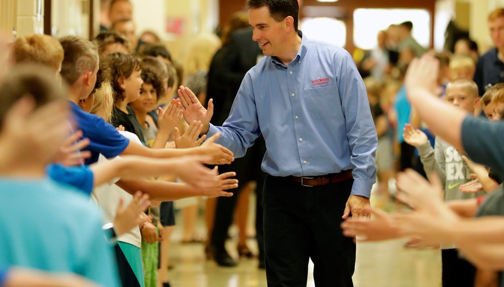 Gov. Scott Walker high-fived students after signing the 2017-'19 state budget bill into law. He touted an increase in state aid to schools, but previously he made cuts. (Dan Powers/USA TODAY NETWORK-Wisconsin)