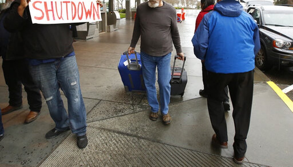 A man heading into the Sacramento International Airport passes demonstrators calling for President Donald Trump and Washington lawmakers to end the shutdown. (AP Photo/Rich Pedroncelli)