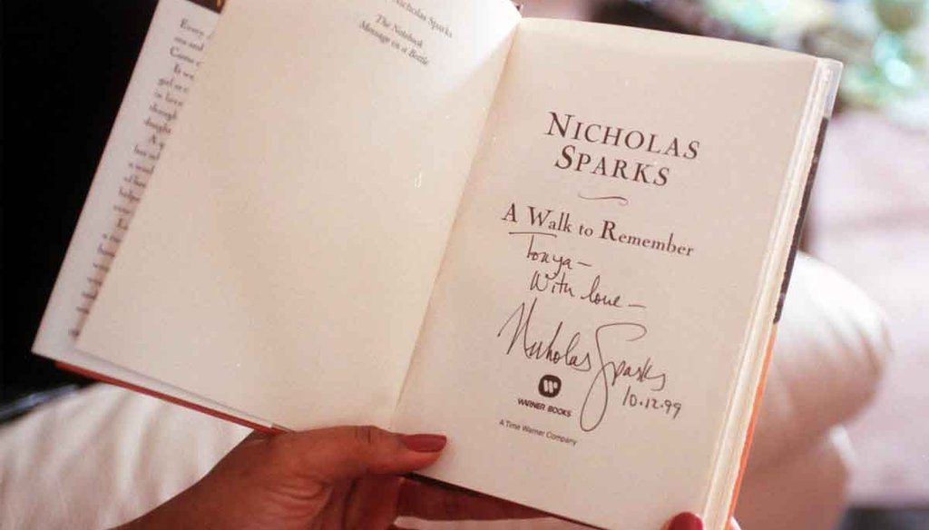 A Raleigh, North Carolina woman passes around her autographed copy of "A Walk to Remember," by Nicholas Sparks at a book club meeting. Photo by The News & Observer.