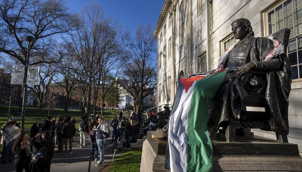 Students protesting against the war in Gaza, and passersby walking through Harvard Yard, are seen next to the statue of John Harvard, draped in the Palestinian flag, at an encampment at Harvard University in Cambridge, Mass., on April 25, 2024. (AP)