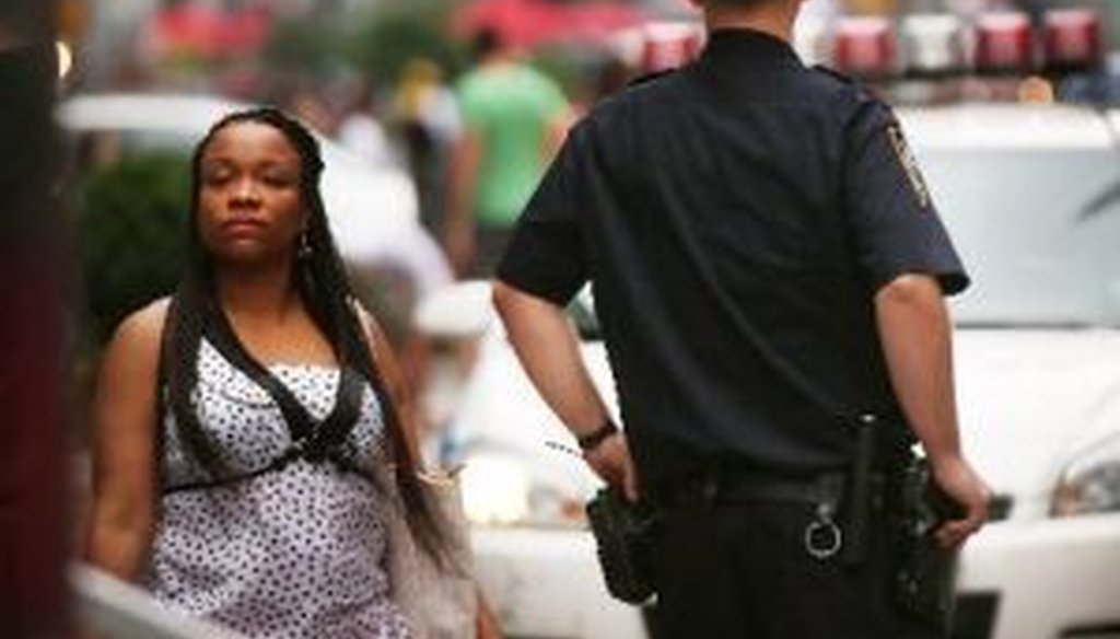 A woman walks by a New York City police officer in Times Square, shortly after the city's "stop and frisk" policy in high crime neighborhoods was given a severe rebuke.