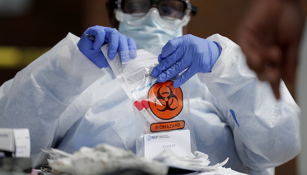 A registered medical assistant handles a nasal swab specimen after it was collected at a drive-thru COVID-19 testing site on April 16, 2020, in St. Louis. (Associated Press)