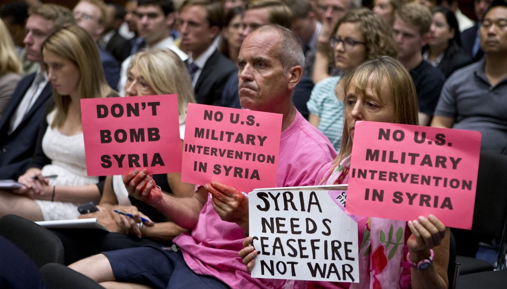 Protestors hold signs during a Sept. 3, 2013 hearing on Capitol Hill against U.S. military intervention in Syria. Photo credit: Associated Press.