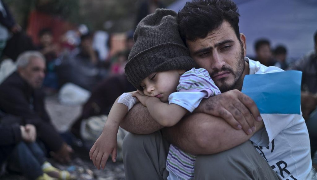 A Syrian refugee carries a baby over the broken border fence into Turkey on June 14, 2015. ( AP/Lefteris Pitarakis)