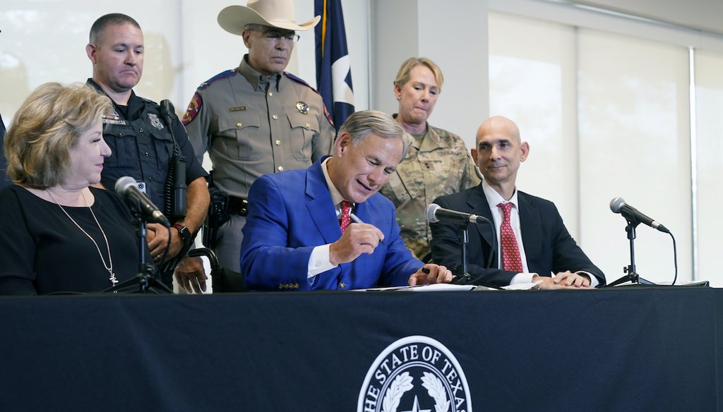 Texas Gov. Greg Abbott, front center, is flanked by State Sen. Jane Nelson and Rep. Greg Bonnen with others looking on as he signs a bill that provides additional funding for security at the U.S.-Mexico border Friday, Sept. 17, 2021, in Fort Worth. (AP)