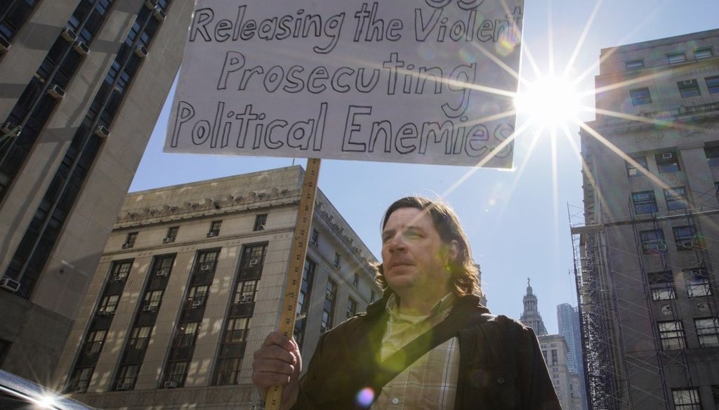 A man holds a poster near the courthouse in New York City on March 20, 2023. (AP)