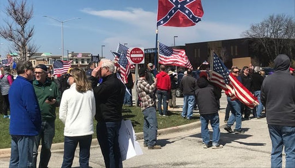 One man attending an April 18, 2020, rally in Brookfield, Wis., to protest coronavirus stay-at-home orders carried a Don't Tread on Me flag and a Confederate flag. (Milwaukee Journal Sentinel)