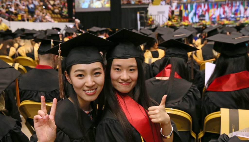 Yixuan Wang (left) and Ke Xiao celebrated their graduation from the University of Wisconsin-Milwaukee, one of the UW System campuses, on May 17, 2015. The UW System faces cuts under the proposed 2015-'17 Wisconsin state budget. (Michael Sears photo)